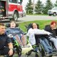 group of people in wheelchairs pose with firefighters