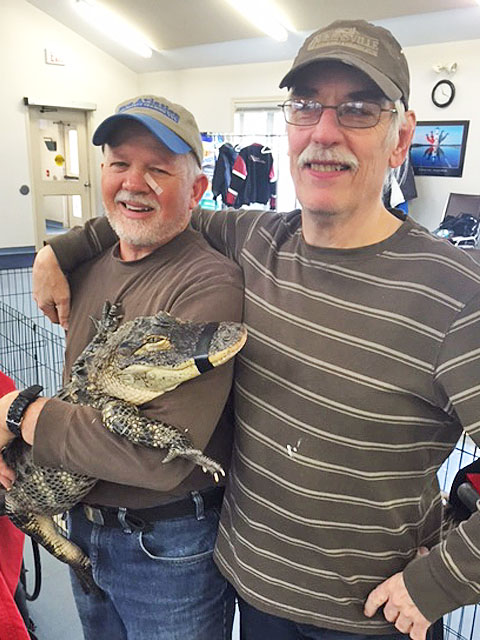 Two men holding an alligator