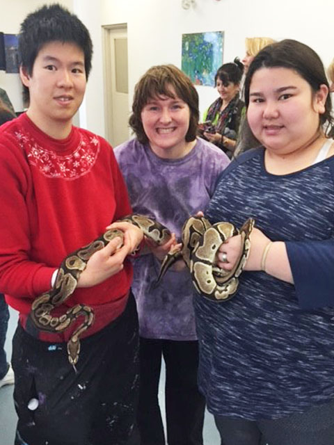 Three ladies holding a snake